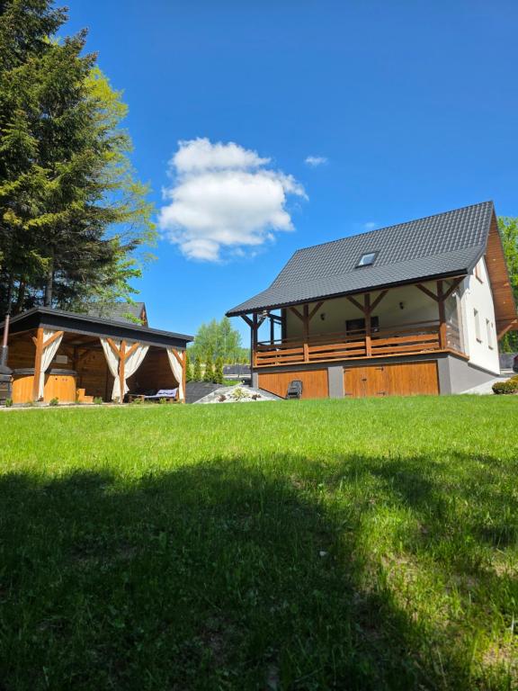 a house with a gambrel roof and a green lawn at Domek letniskowy Leśne Zacisze- jacuzzi, balia ogrodowa, grill i altana in Słopnice