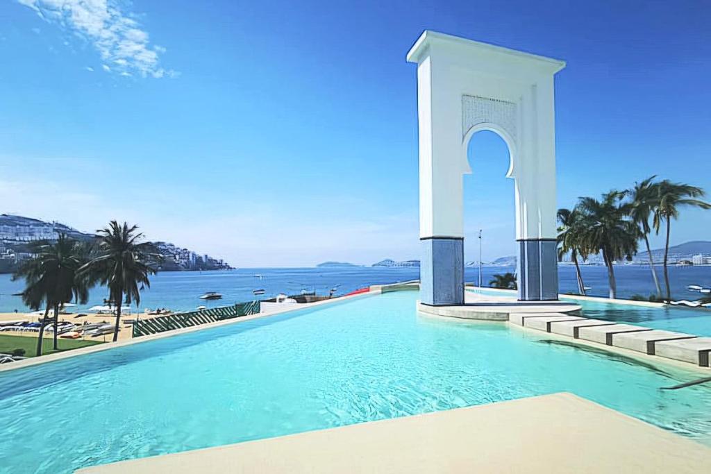 a swimming pool with the ocean in the background at Playa Acapulco Espectacular Apartment in Acapulco