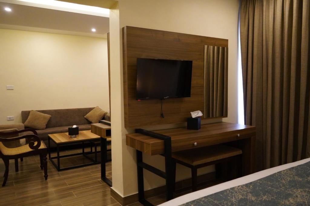 a hotel room with a couch and a television at POST Hotel Amman in Amman