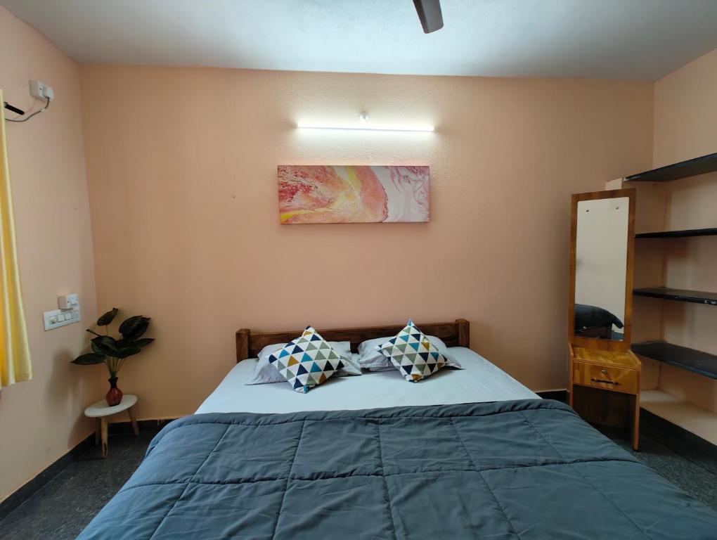 a bedroom with a bed with blue sheets and pillows at Hamsa Farmstay - 2BHK AC Homestay in Mysore