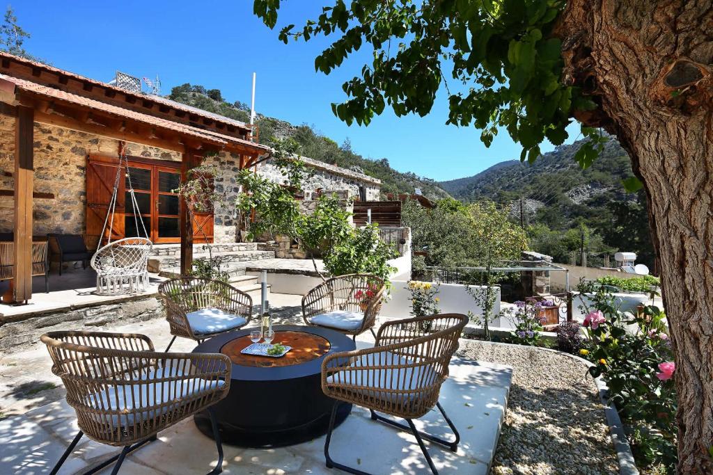 a patio with a table and chairs and a tree at Blue Cottage in Apsiou