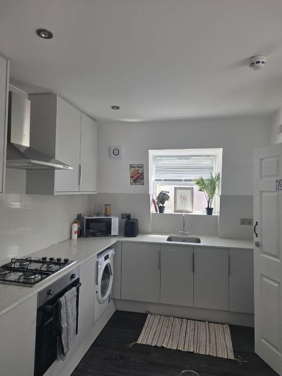 a white kitchen with a sink and a stove at Fulham Guest Studios 268 in London