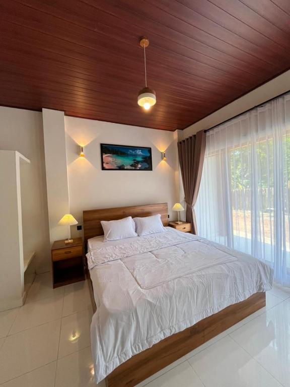 a bedroom with a large bed with a wooden ceiling at KUTA GLORI Homestay in Kuta Lombok