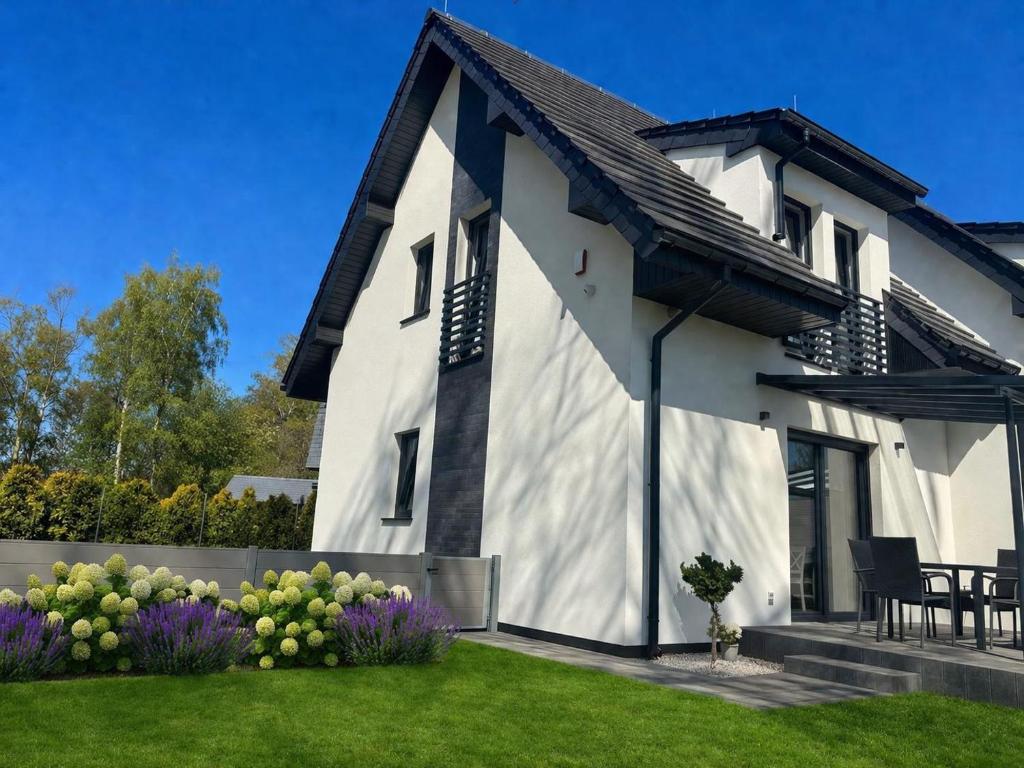 a white house with a black roof at Villa LUX Luis in Dziwnów