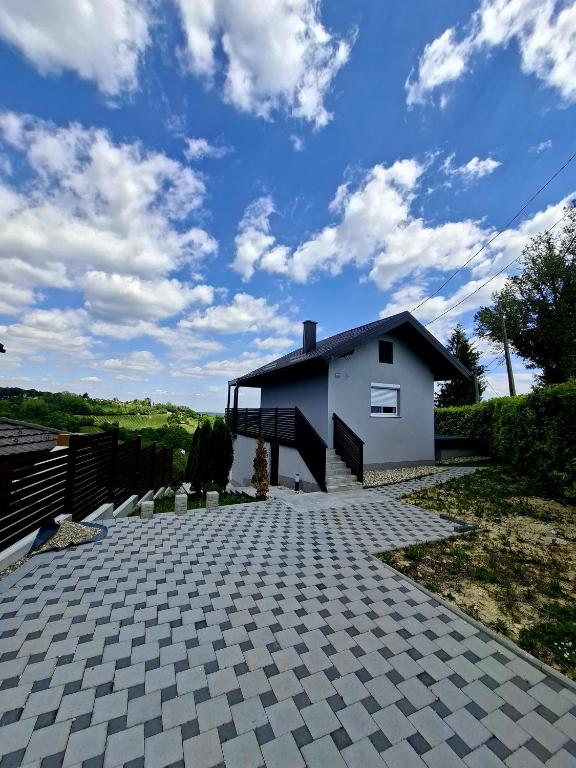 a house with a brick driveway in front of a building at KUĆA za odmor 128 in Plešivica