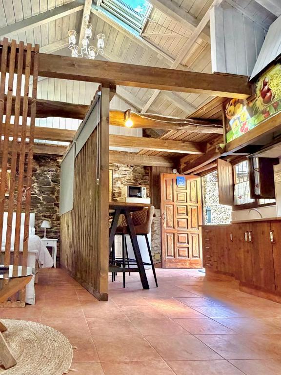 a living room with a table and a wooden ceiling at CASA FOLIBAR-Encanto rural entre piedra y madera Valle del Silencio in Manzanedo de Valdueza
