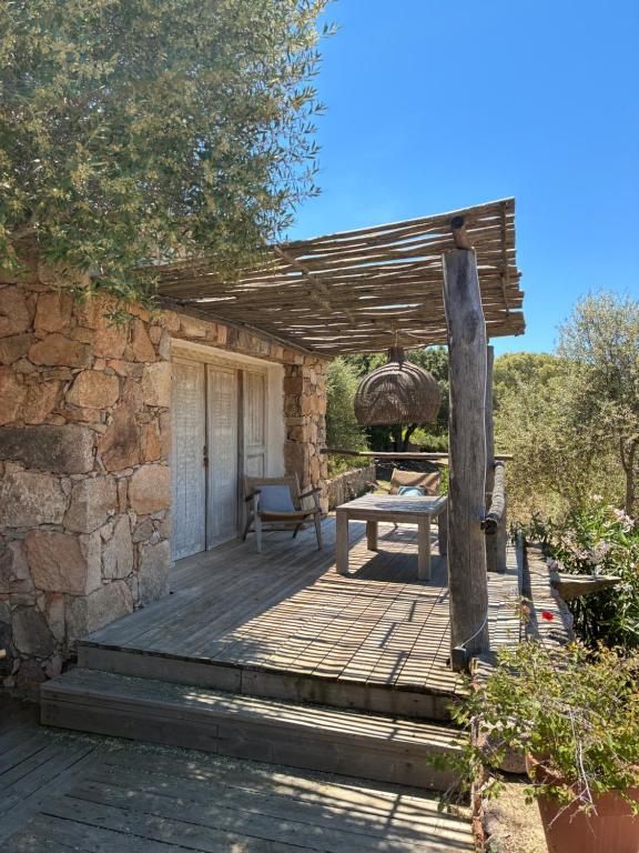 a wooden deck with a bench and a stone wall at Chambre bergerie privée in Sartène