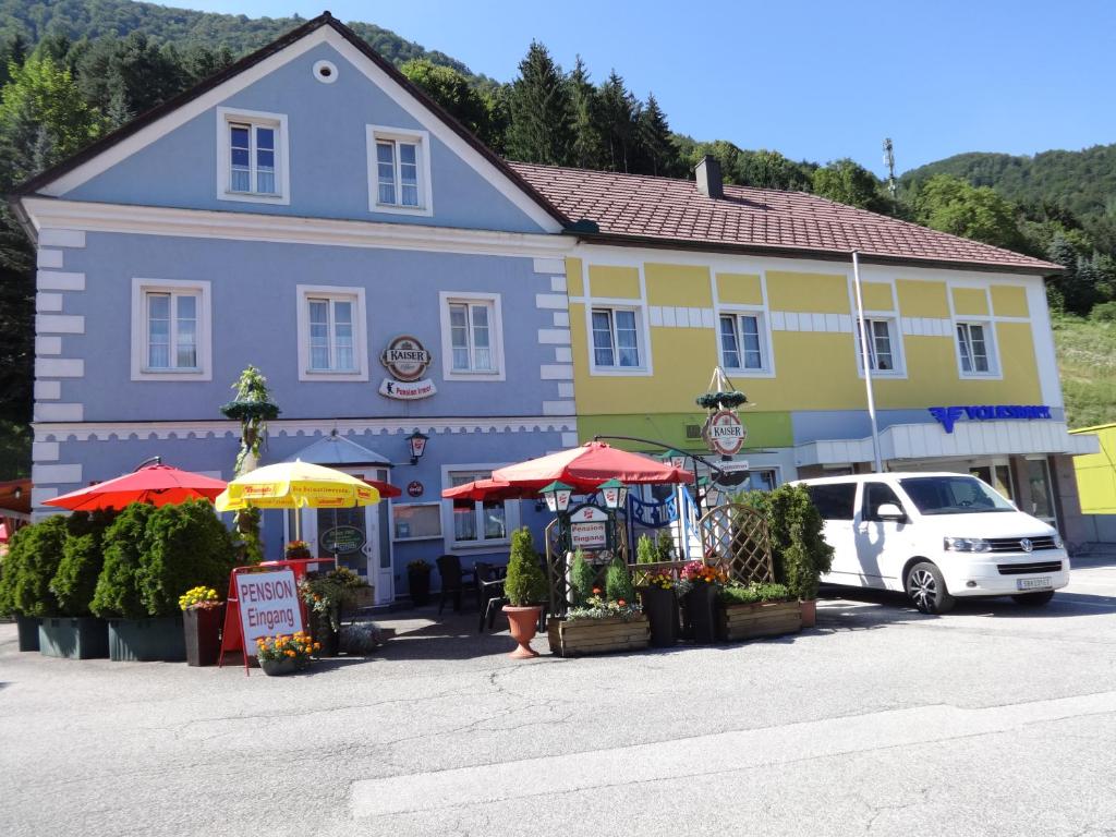 un edificio azul y amarillo con sombrillas delante en Frühstückspension Irmer en Gaming