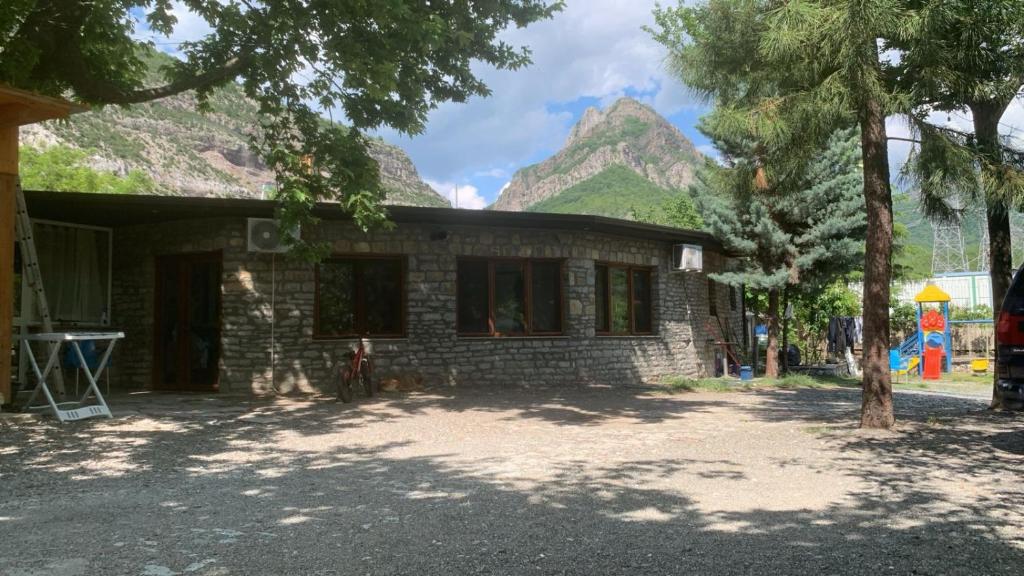 a small brick building with a mountain in the background at Natura Koman in Koman