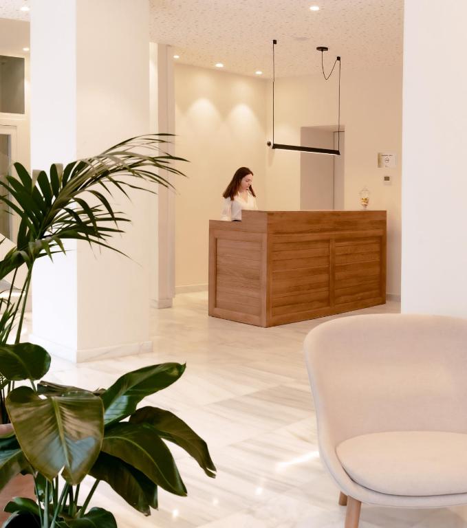 a woman standing at a reception desk in a lobby at B&H Boreal in Burgos