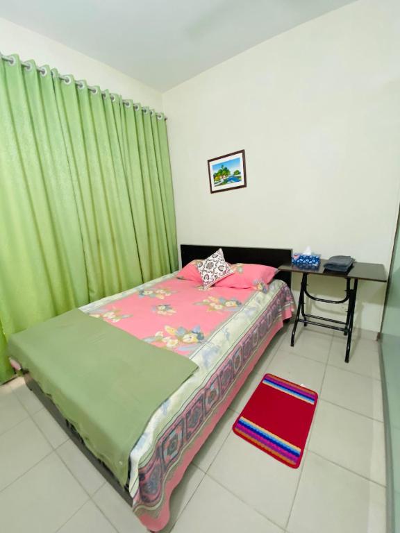 ein Schlafzimmer mit einem Bett mit grünem Vorhang und einem Tisch in der Unterkunft ADD Eden in Dhaka