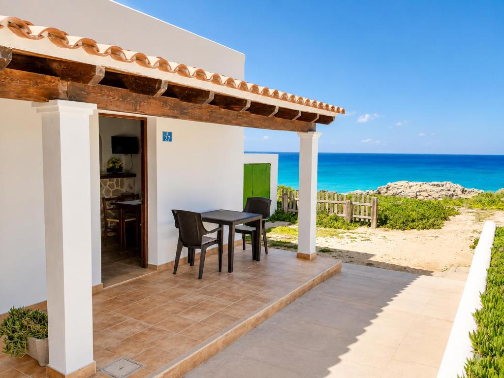 a patio with a table and chairs and the ocean at Can Joan Robert des Mestre in Es Caló
