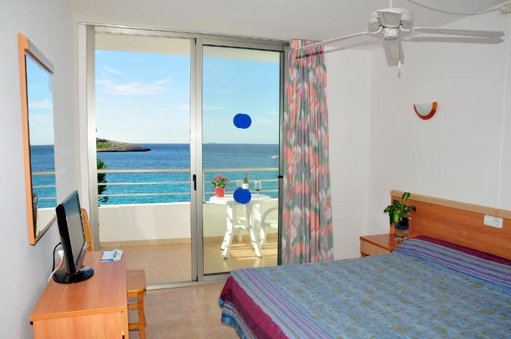 una camera con letto e vista sull'oceano di S'Arenal Apartments a Portinatx