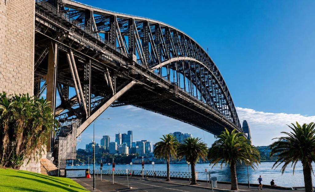 a bridge over the water with palm trees and a city at Opera House Retreat - Opera House & Bridge View in Sydney