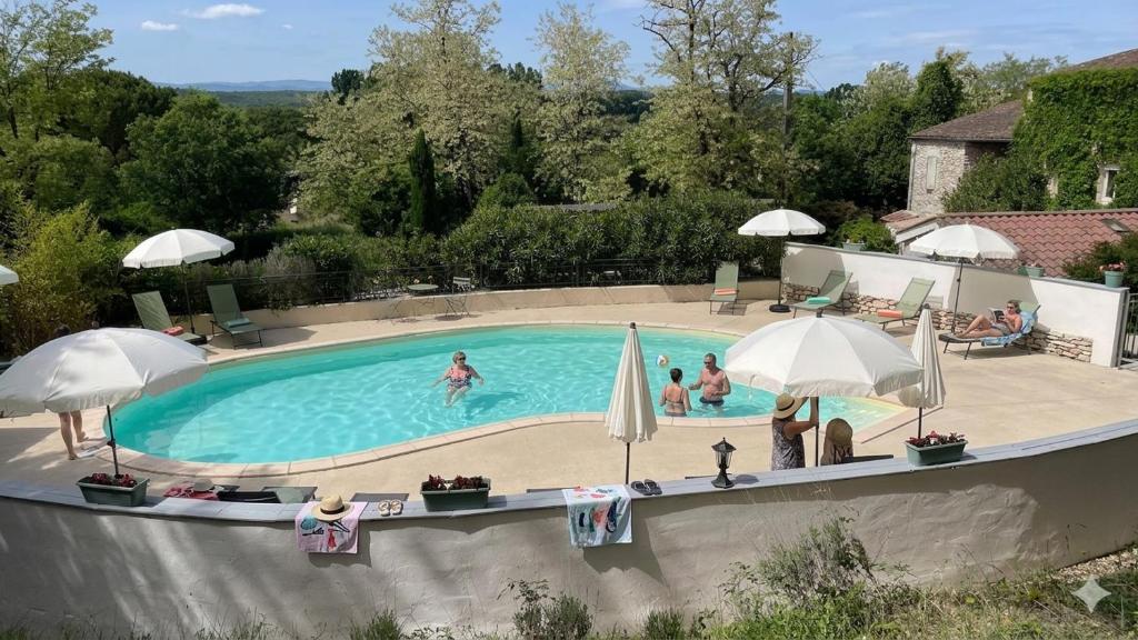 a swimming pool with people in it with umbrellas at Le Mas de la Colombe in Grospierres