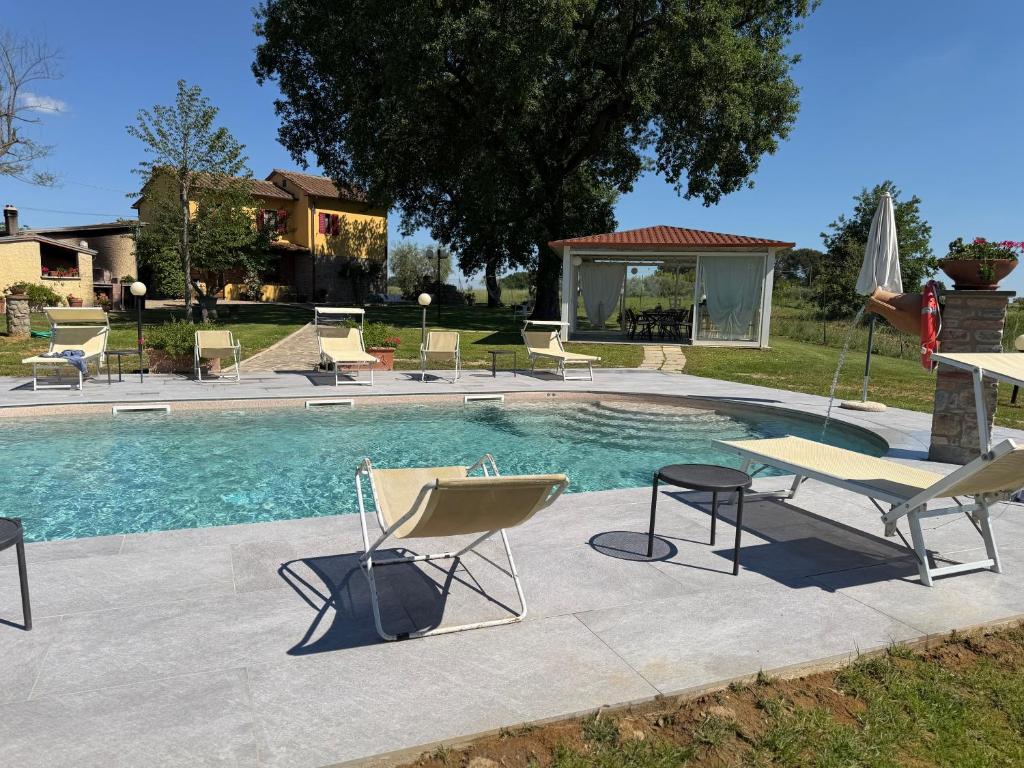 a swimming pool with two chairs and a table and chairs at Agriturismo Podere Delle Querci in Castiglion Fiorentino