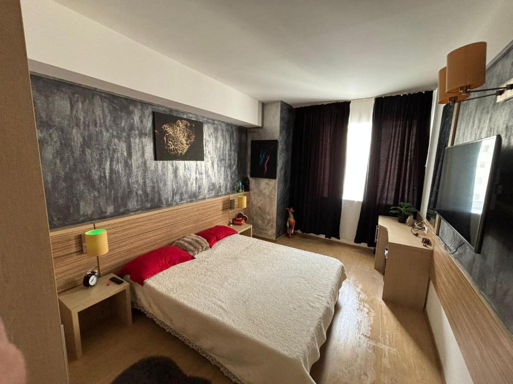 ein Schlafzimmer mit Bett und Flachbildfernseher in der Unterkunft FabiRooms in Bukarest