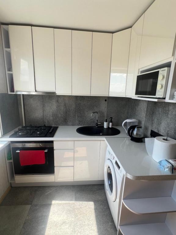 a kitchen with white cabinets and a sink and a stove at Deividas apart in Vilnius