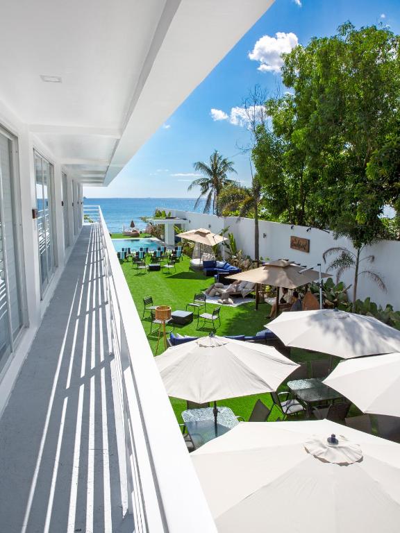 ein Balkon mit Tischen und Sonnenschirmen und dem Meer in der Unterkunft The Beachfront Bataan in Morong