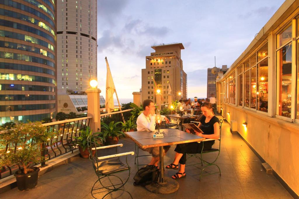 mężczyzna i kobieta siedzący przy stole na balkonie w obiekcie Colombo City Hotels (Pvt) Ltd w Kolombo
