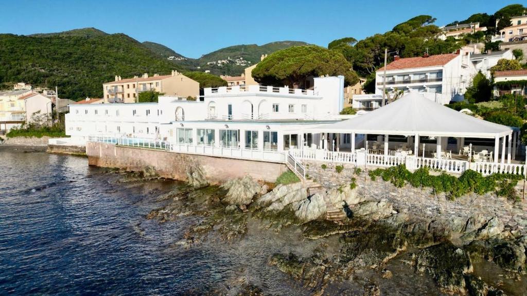 a large white building next to a body of water at Hotel Ariana in Marine du Miomo