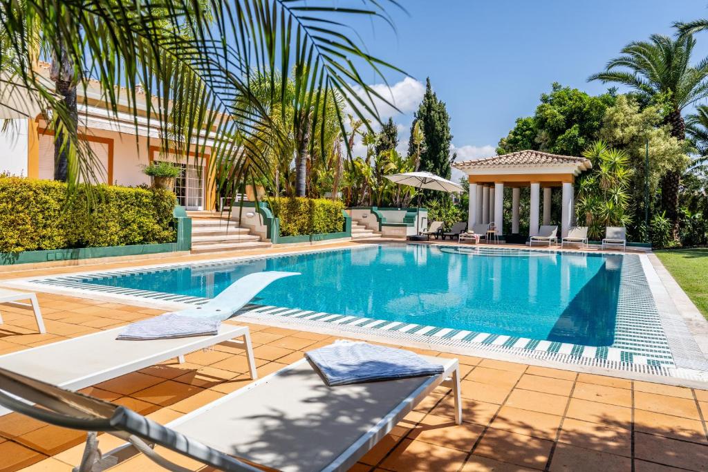 a swimming pool with chairs and a house at CICAS VILLA in Albufeira
