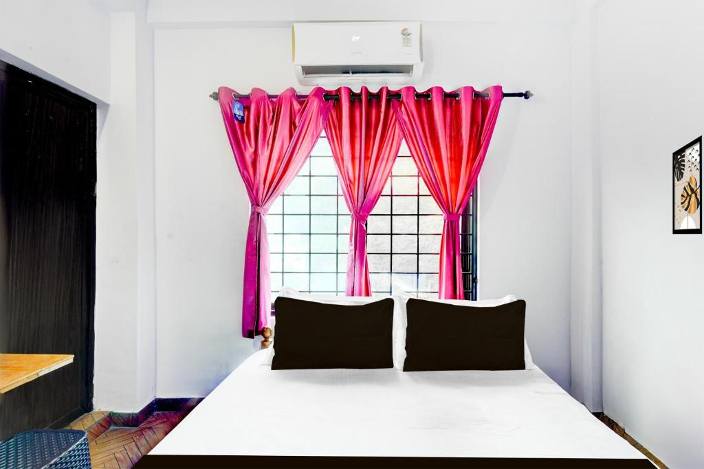 a bedroom with a bed with a window with pink curtains at Hotel O A Star Lodge in Trichūr