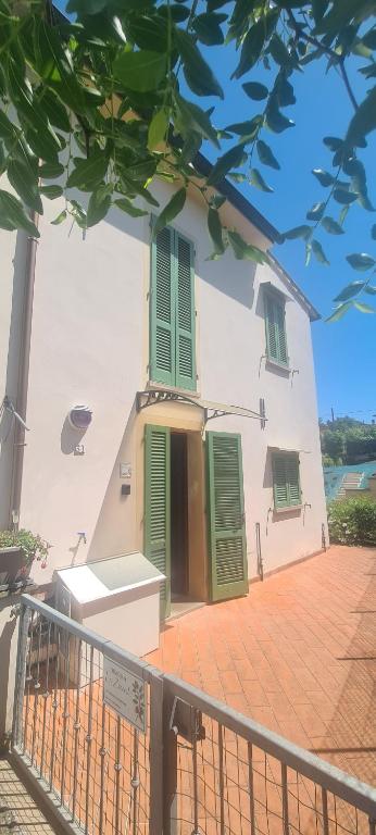 a white house with green shutters and a porch at Dimora Lo Zizzolo - Casa vacanze indipendente vicino Pontedera in Pontedera