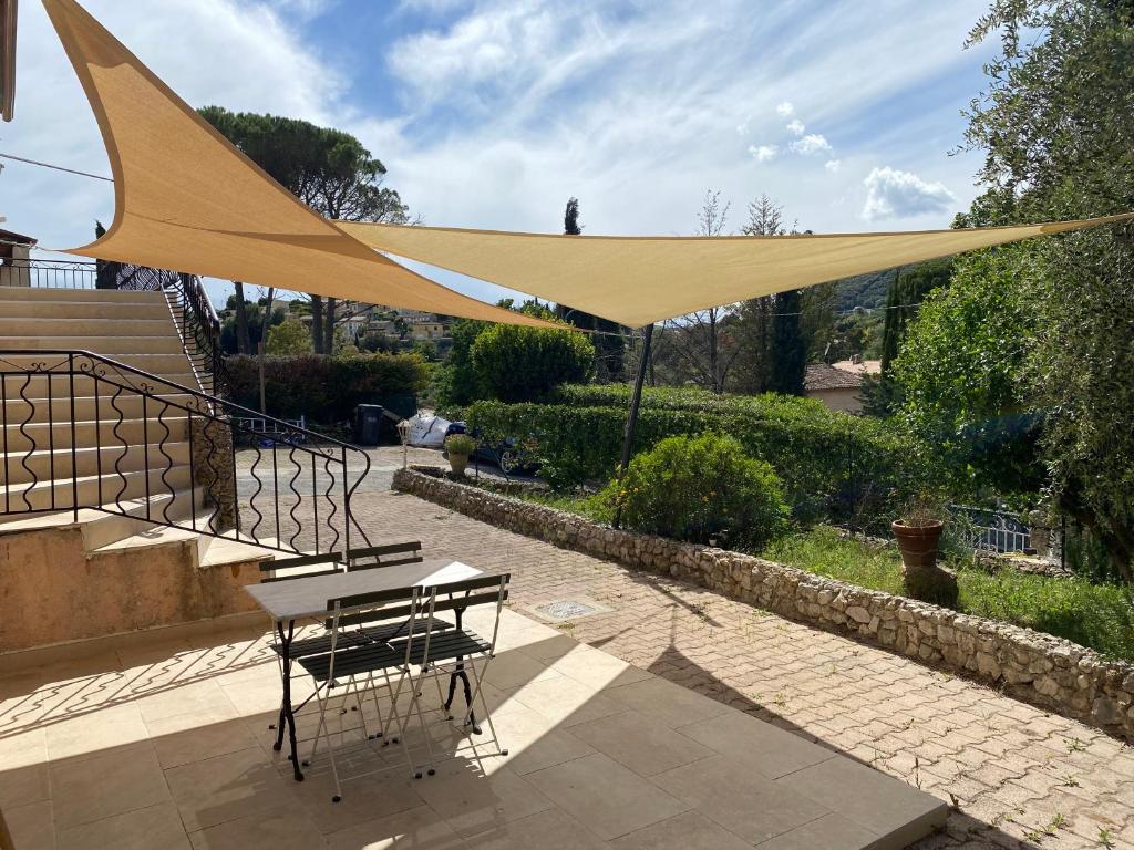 a yellow canopy over a table and chairs on a patio at Spacieux 2 pièces, au calme in Le Tignet