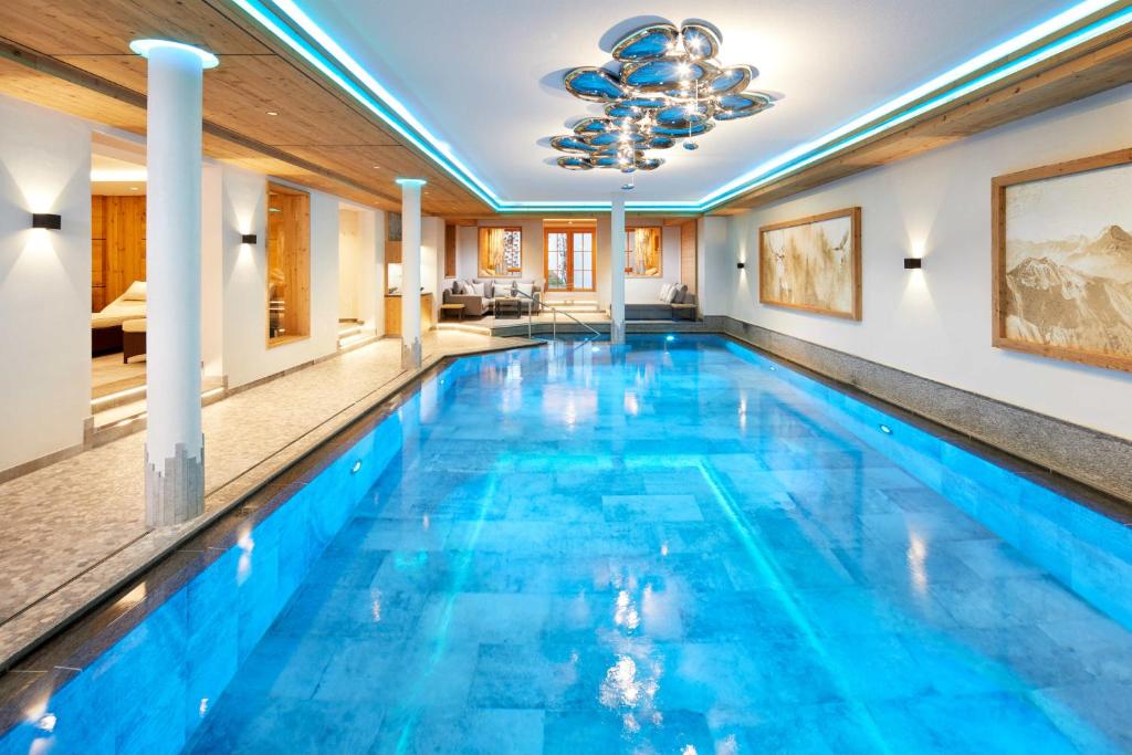 a swimming pool in a house with blue water at Hotel Gletscherblick in Sankt Anton am Arlberg