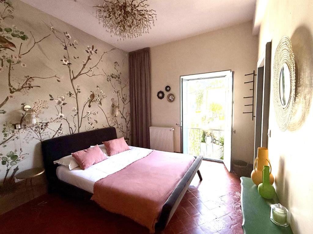 a bedroom with a bed with pink sheets and a window at L'Oiseau Bleu ROLLIER in Roubia