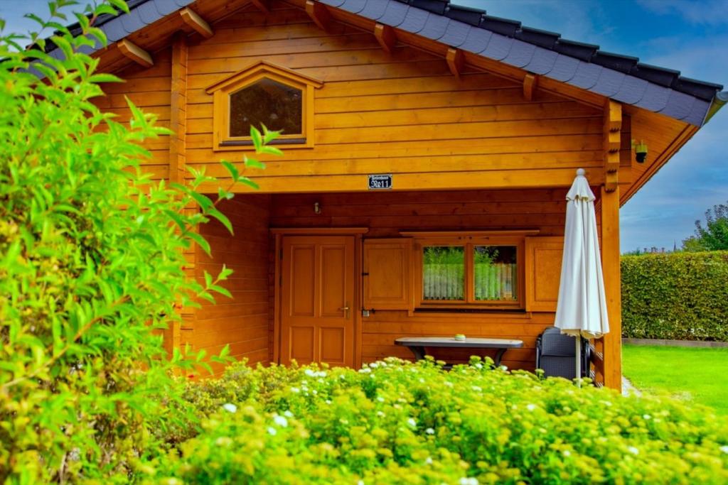 a wooden cabin with an umbrella and a table at Waldsiedlung - Haus 11 in Senftenberg