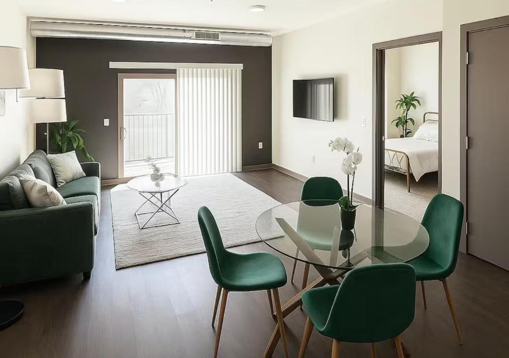a living room with a glass table and green chairs at Evergreen Nook in Des Moines