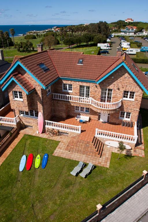 a large brick house with a yard with frisbees at Gijon Surf Hostel in Gijón