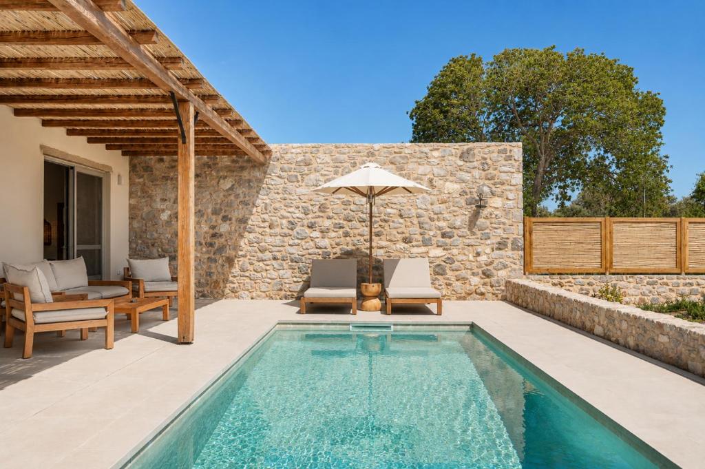 an outdoor pool with chairs and an umbrella at Elion Private Pool Villas in Kos