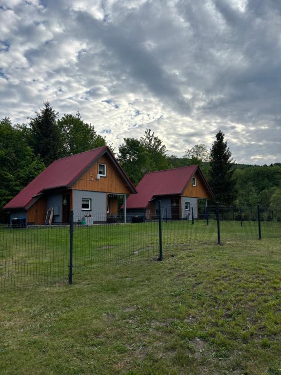 a couple of barns in a field with a fence at Górski Oddech - Domki u Danki in Brenna