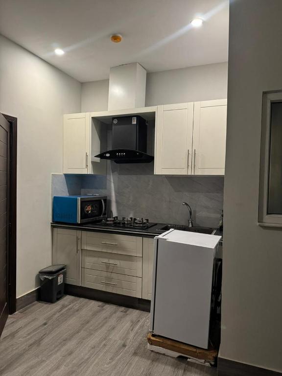 a kitchen with white cabinets and a white refrigerator at Seven Star Heights in Rawalpindi