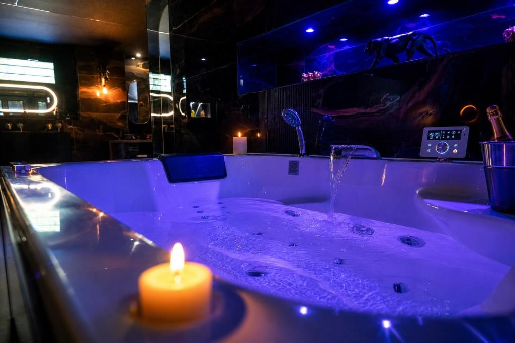 a lit candle in a bath tub with a lit candle at Baobab Logement Atypique avec jacuzzi privé in Corbas