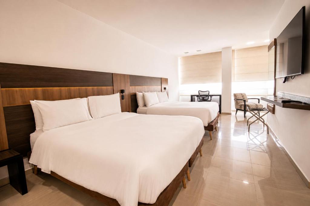 a hotel room with two beds and a television at San Simon Hotel Pereira By Soratama in Pereira
