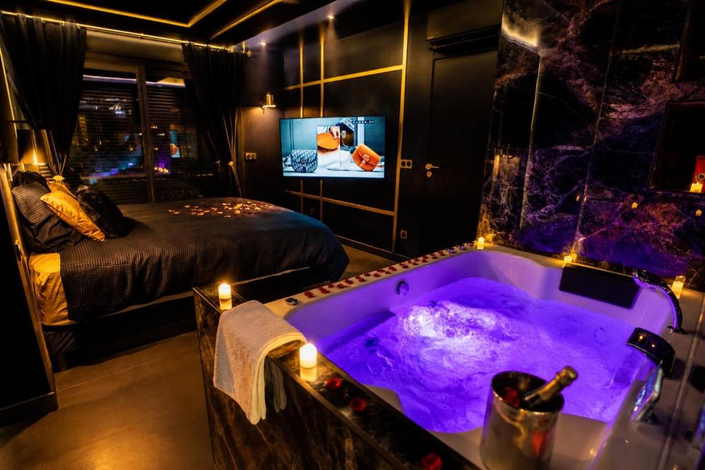 a room with a tub and a bed and a tv at Minka Cocon Atypique avec jacuzzi privé in Corbas