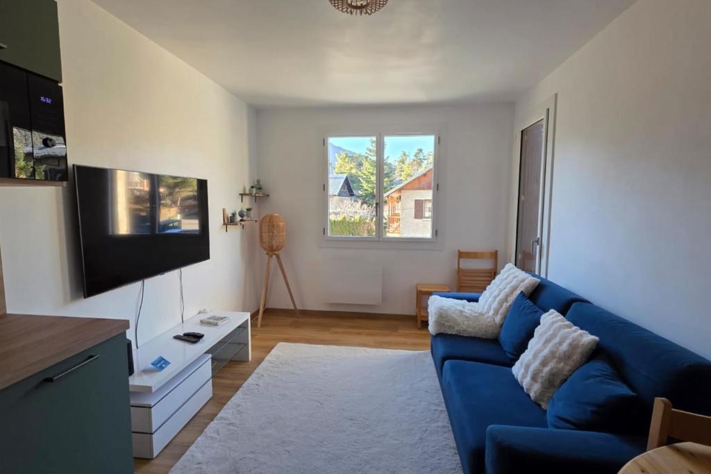 a living room with a blue couch and a tv at Charming apartment overlooking the valley in Briançon
