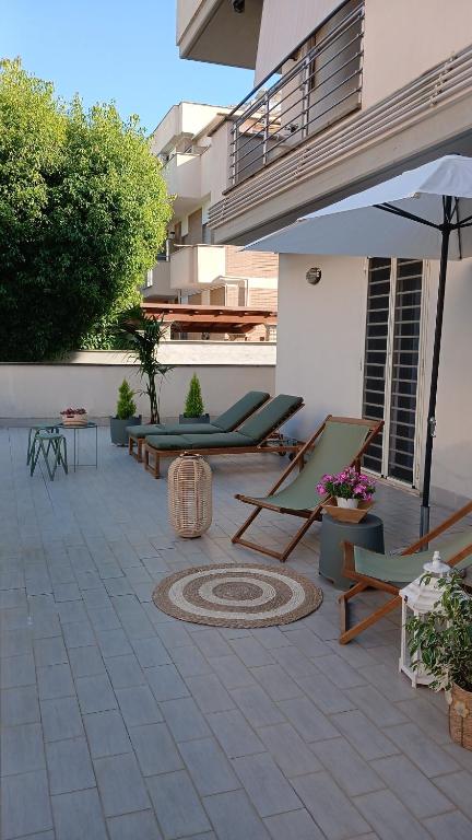 a patio with lounge chairs and an umbrella at Fantasticasa in Nettuno