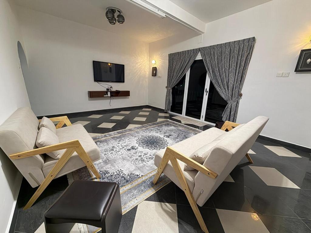 a living room with two chairs and a tv at AmaniStay Cameron Highlands in Cameron Highlands