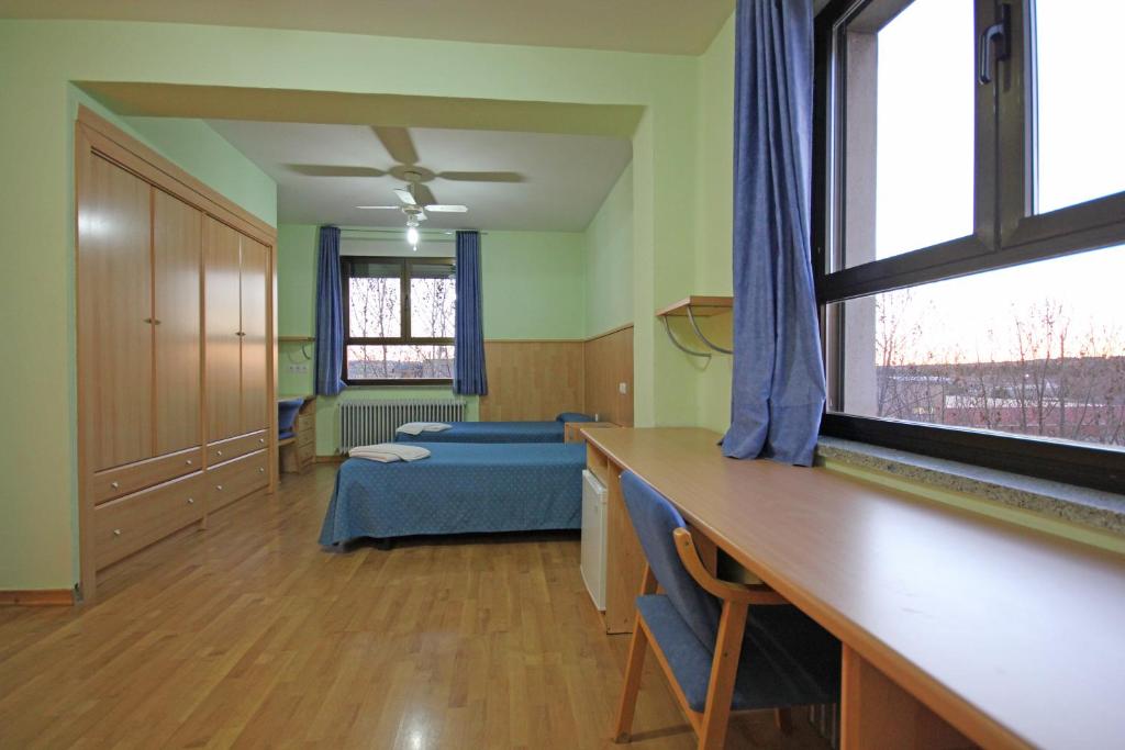 Habitación con dormitorio con cama y ventana en Residencia Universitaria Cum Laude, en Salamanca