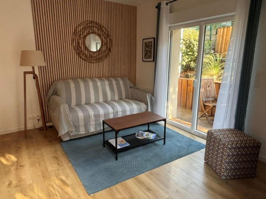a living room with a couch and a table at 3 pièces avec terrasse arborée in Arcachon