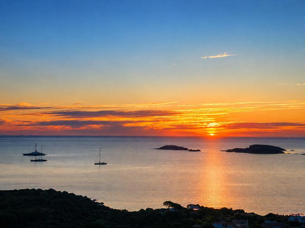 a sunset over the ocean with boats in the water at Big Pevero Sea View House 8 Three Bedrooms in Porto Cervo