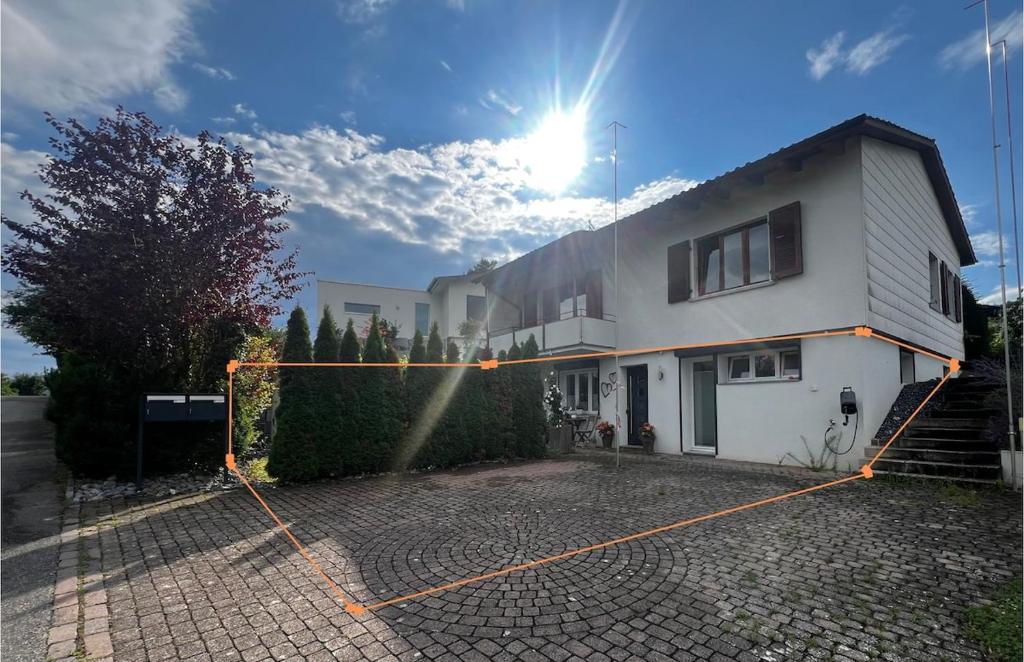 a white house with a fence in front of it at Modern apartment with garden in Lostorf