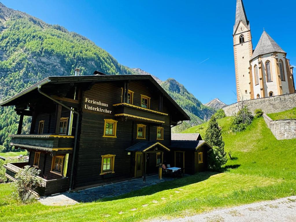 a wooden building on a hill next to a church at Ferienhaus Unterkircher-Wallner in Heiligenblut
