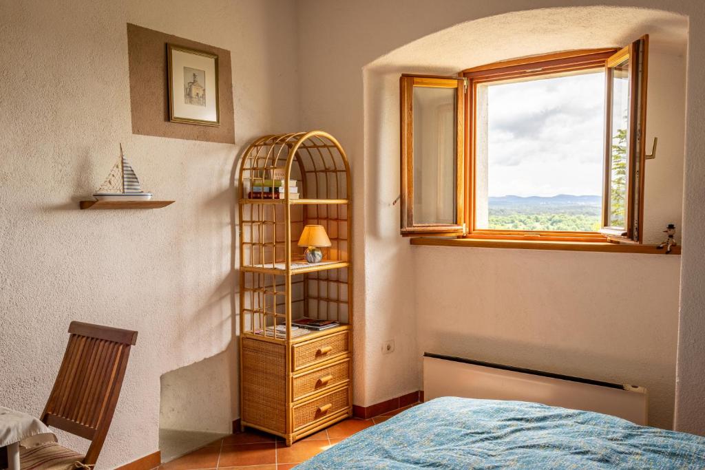 a bedroom with a book shelf and a bed and a window at Štanjelski Razgledi AR in Štanjel