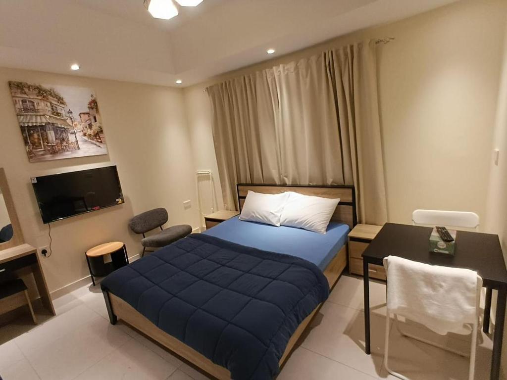 a hotel room with a blue bed and a desk at KAYAN ALAMAL HOTEL dubai in Dubai